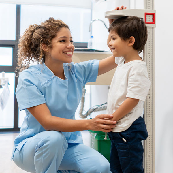 Female medical assistant measures height of young male patient Female medical assistant measures height of young male patient
