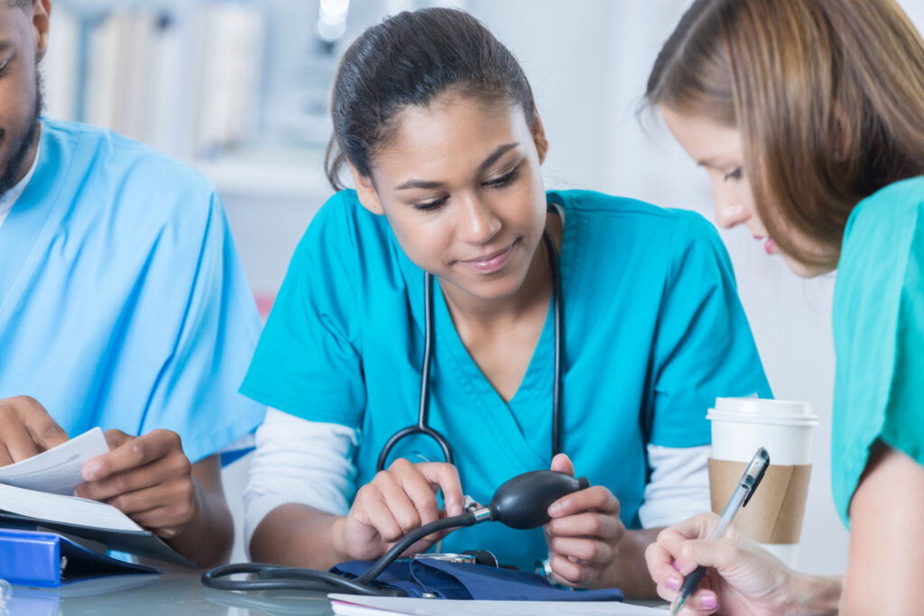 a medical professional in scrubs holding a blood pressure cuff